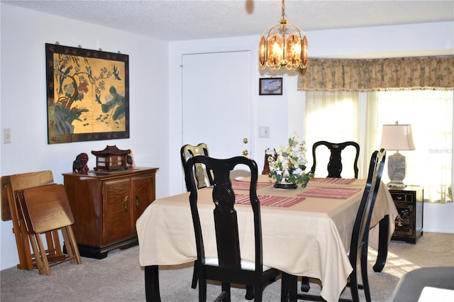 dining area featuring a chandelier, light carpet, and a textured ceiling