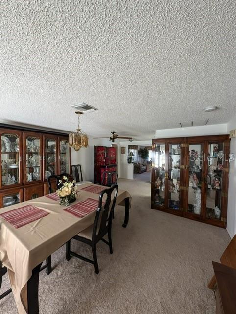 dining space featuring light carpet and a textured ceiling