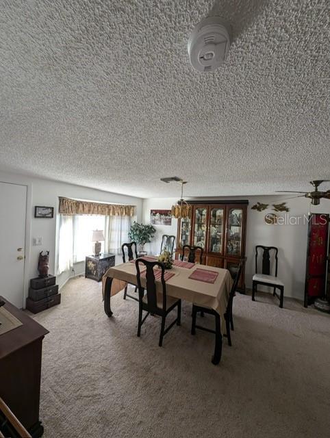 carpeted dining area featuring a textured ceiling