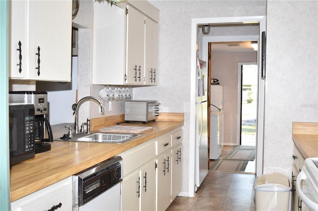 kitchen featuring sink, white cabinetry, dishwasher, separate washer and dryer, and tile patterned floors