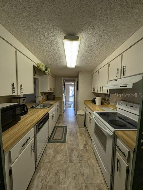 kitchen featuring sink, white appliances, wood counters, and white cabinets