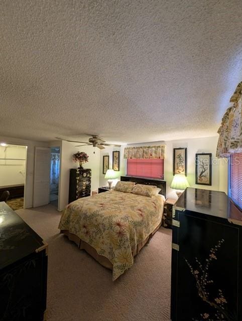 carpeted bedroom featuring ceiling fan and a textured ceiling