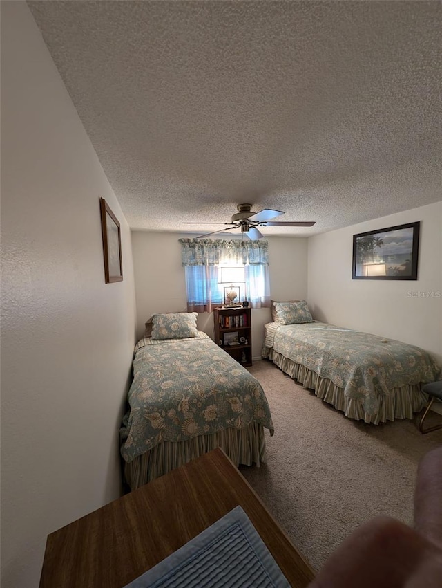 bedroom with ceiling fan, carpet flooring, and a textured ceiling