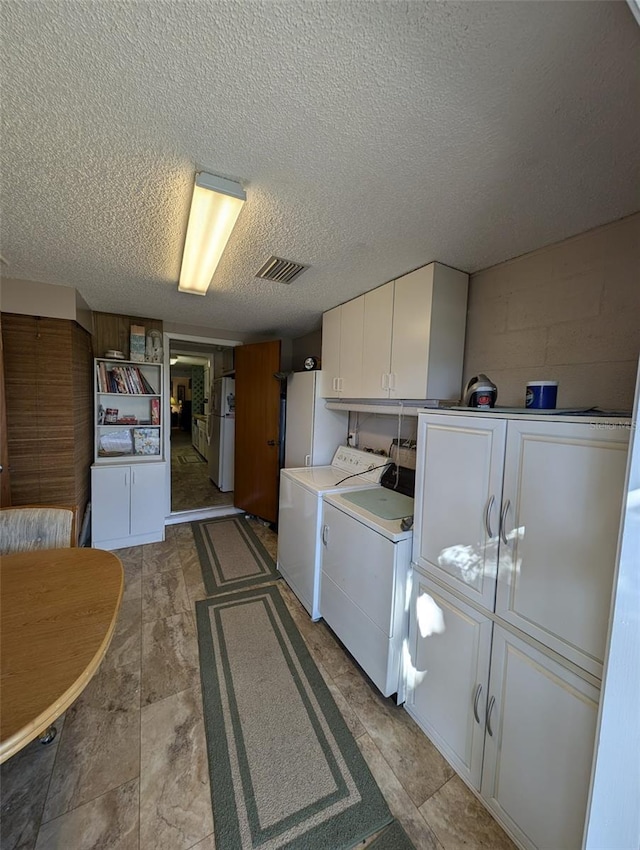 laundry room with a textured ceiling, cabinets, and independent washer and dryer