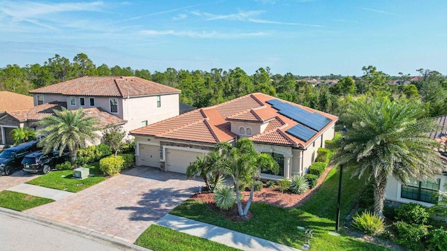 mediterranean / spanish-style house featuring a garage, a front yard, and solar panels