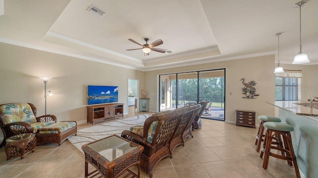 tiled living room featuring crown molding, a raised ceiling, and ceiling fan