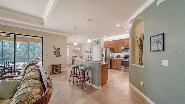 kitchen with a kitchen bar, light stone counters, decorative light fixtures, a center island with sink, and appliances with stainless steel finishes