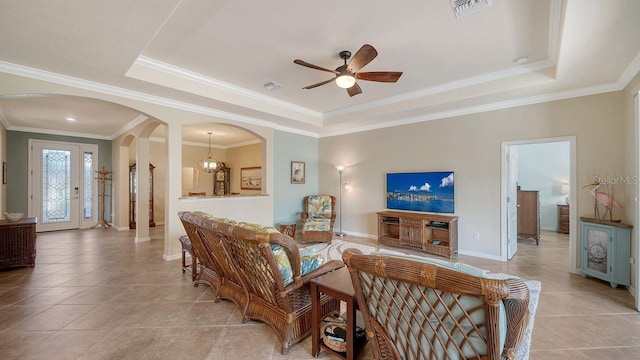 tiled living room featuring a tray ceiling, ceiling fan with notable chandelier, and ornamental molding