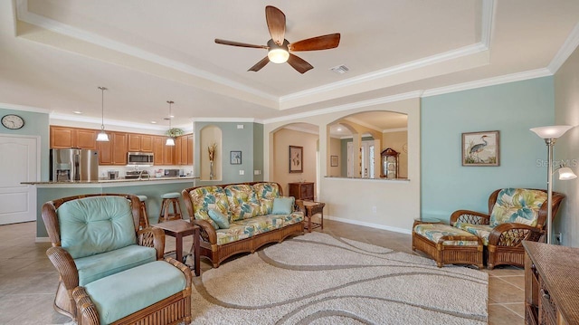 living room with light tile patterned floors, crown molding, a raised ceiling, and ceiling fan