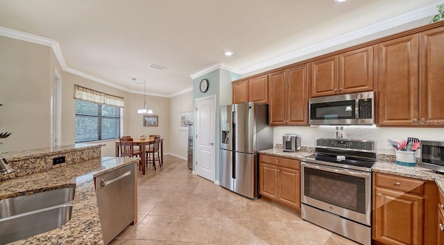 kitchen with stainless steel appliances, light stone countertops, sink, and pendant lighting