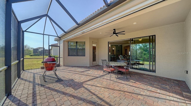 view of patio with ceiling fan and glass enclosure