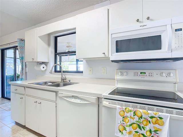 kitchen featuring light tile patterned flooring, sink, a textured ceiling, white appliances, and white cabinets