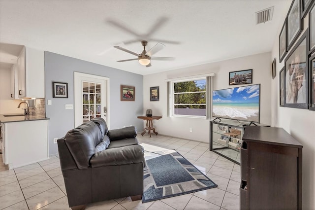 living room with light tile patterned flooring, sink, and ceiling fan