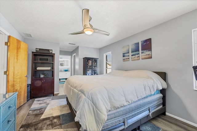 bedroom with ceiling fan, dark hardwood / wood-style floors, and a textured ceiling