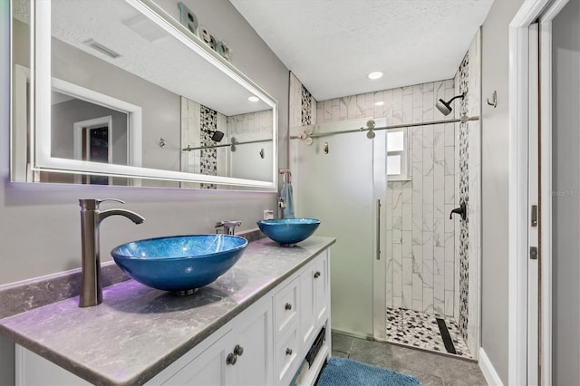 bathroom with vanity, a shower with shower door, and a textured ceiling