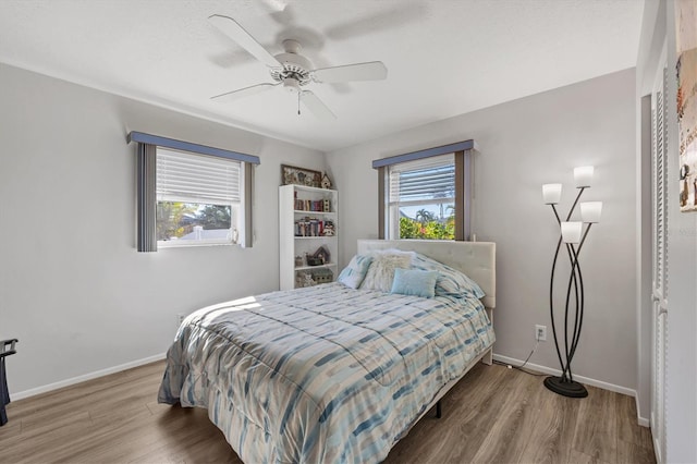 bedroom with multiple windows, hardwood / wood-style floors, and ceiling fan