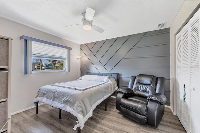 bedroom with ceiling fan, a closet, hardwood / wood-style floors, and a textured ceiling