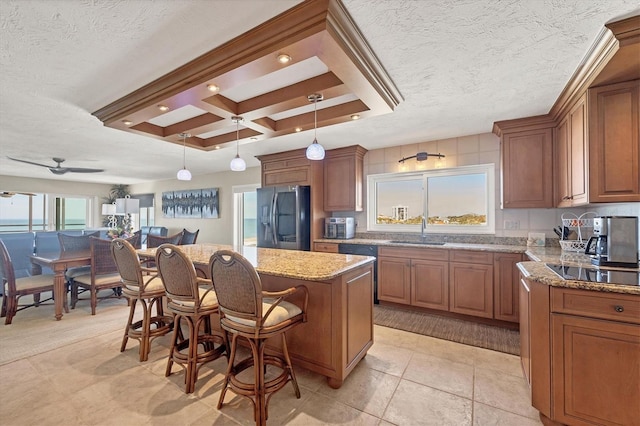 kitchen with a breakfast bar, sink, decorative light fixtures, a center island, and black appliances