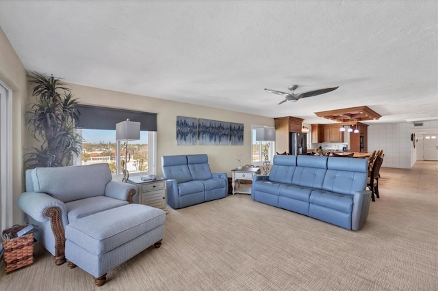 living room with ceiling fan, light colored carpet, and a textured ceiling