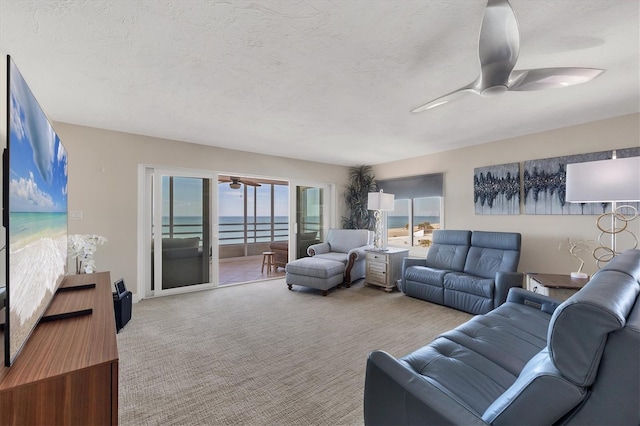 living room with a water view, carpet flooring, a textured ceiling, and ceiling fan