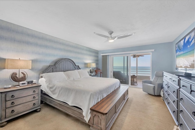 bedroom featuring a water view, ceiling fan, light carpet, and access to outside