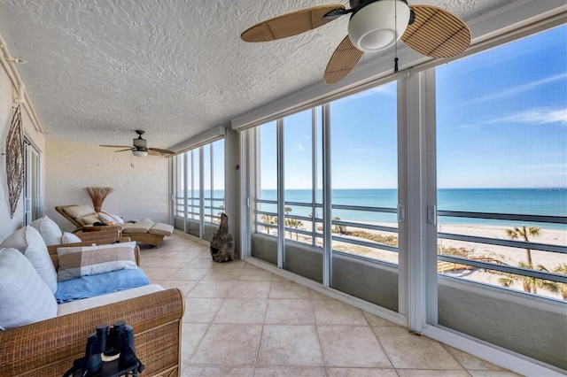 sunroom / solarium with ceiling fan, a beach view, and a water view