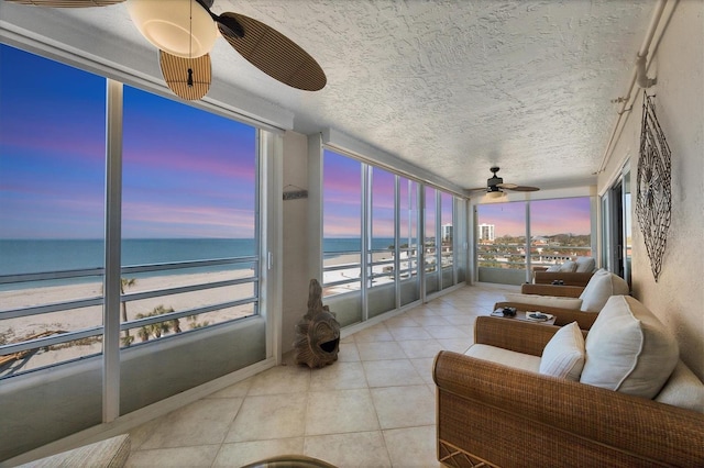 sunroom with a beach view, ceiling fan, and a water view