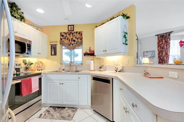 kitchen featuring light tile patterned flooring, sink, appliances with stainless steel finishes, kitchen peninsula, and white cabinets