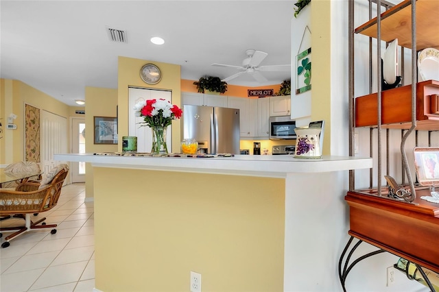 kitchen with appliances with stainless steel finishes, light tile patterned floors, white cabinets, and kitchen peninsula