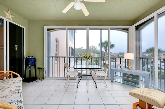 sunroom with a water view and ceiling fan