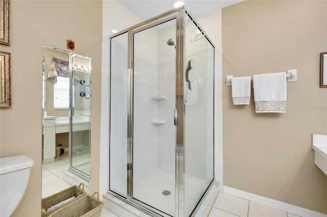 bathroom with a shower with door, vanity, tile patterned floors, and toilet