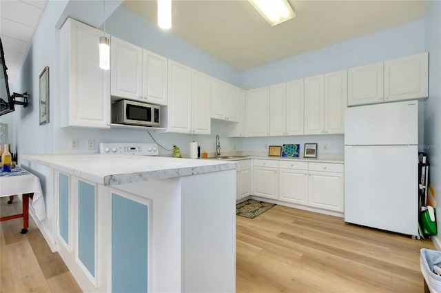 kitchen featuring hanging light fixtures, white cabinetry, white fridge, and kitchen peninsula