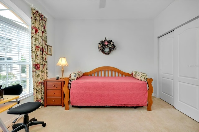 carpeted bedroom featuring multiple windows, ceiling fan, and a closet