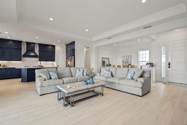 living room featuring a raised ceiling, crown molding, and light hardwood / wood-style floors