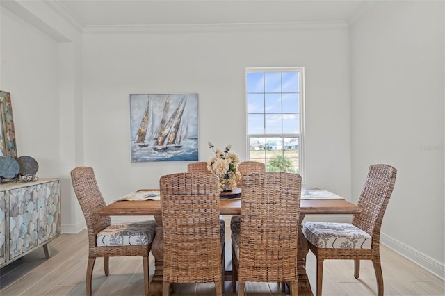 dining space with crown molding and light wood-type flooring