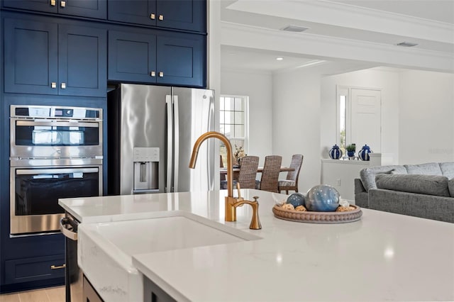 kitchen with sink, ornamental molding, stainless steel appliances, and blue cabinets