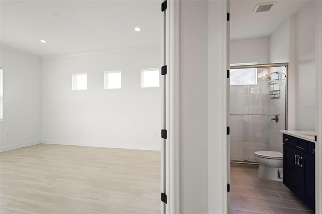 bathroom featuring walk in shower, plenty of natural light, toilet, and vanity