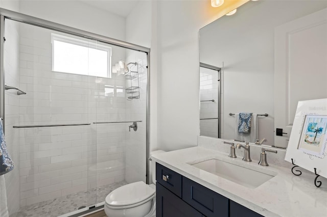 bathroom with vanity, a shower with door, and toilet