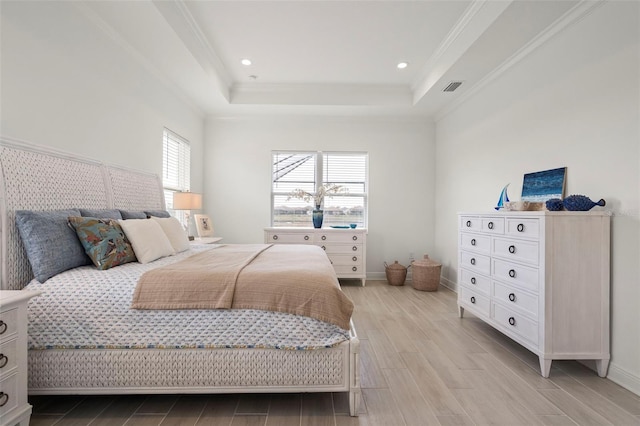 bedroom featuring crown molding, a tray ceiling, and light hardwood / wood-style flooring