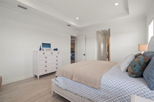 bedroom featuring ornamental molding, light hardwood / wood-style floors, and a tray ceiling