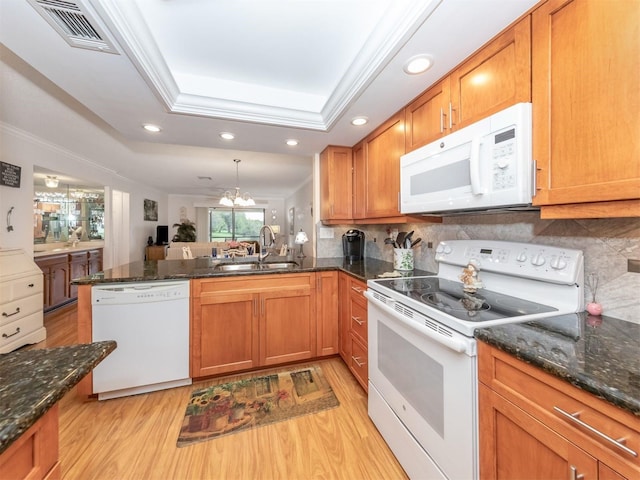 kitchen with decorative light fixtures, sink, kitchen peninsula, a raised ceiling, and white appliances