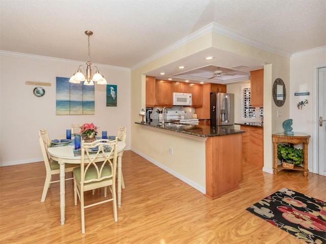 kitchen featuring range, dark stone counters, stainless steel fridge, and kitchen peninsula