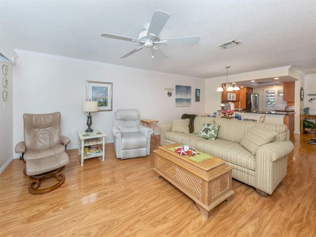 living room with ornamental molding, ceiling fan with notable chandelier, and light hardwood / wood-style floors