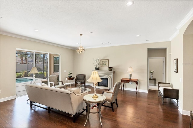 living room with ornamental molding, dark hardwood / wood-style floors, an inviting chandelier, and a textured ceiling