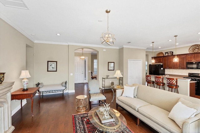 living room featuring crown molding, dark hardwood / wood-style flooring, and an inviting chandelier