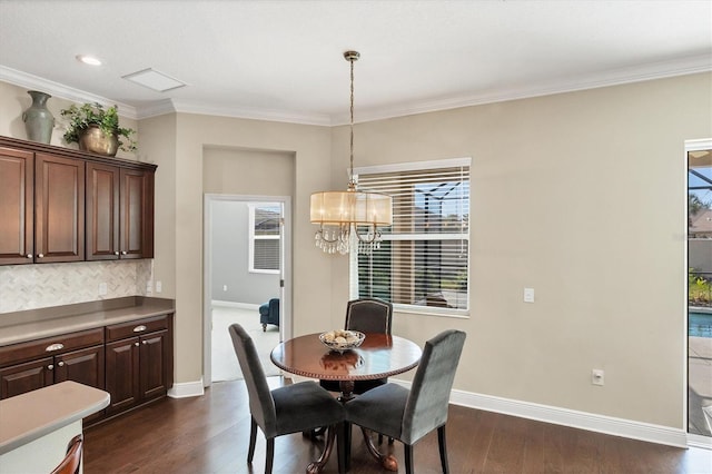 dining space with dark wood-type flooring, ornamental molding, and a chandelier