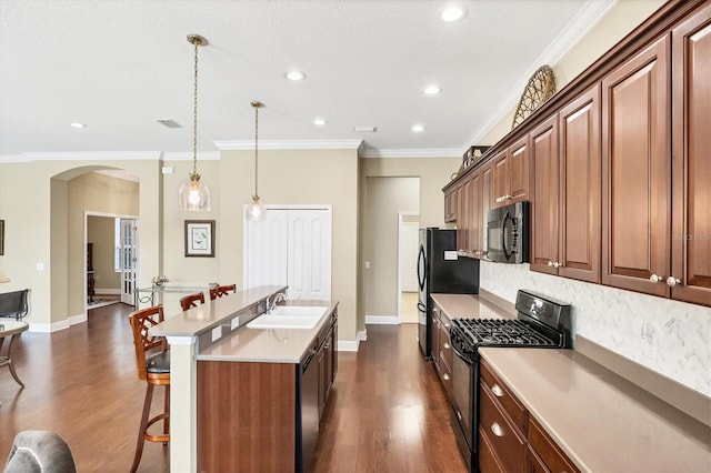 kitchen featuring pendant lighting, an island with sink, sink, backsplash, and black appliances