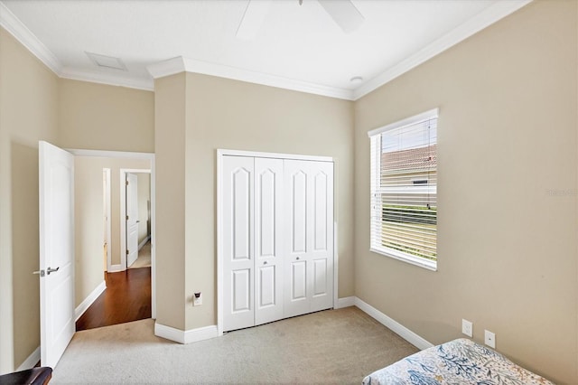 carpeted bedroom featuring ornamental molding, a closet, and ceiling fan