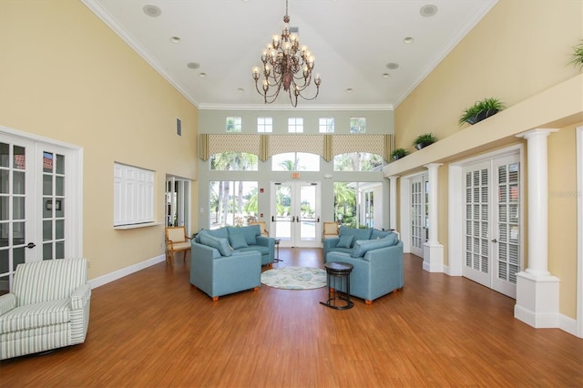 living room featuring french doors, crown molding, hardwood / wood-style floors, and ornate columns