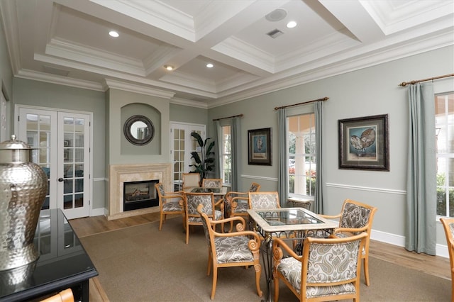 dining room featuring a premium fireplace, beam ceiling, coffered ceiling, french doors, and light wood-type flooring